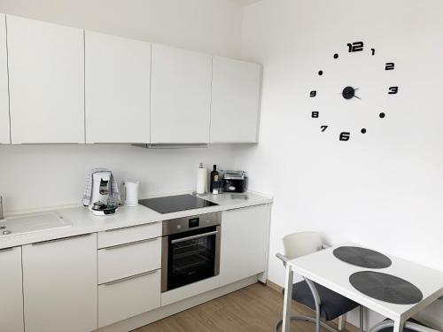 a kitchen with white cabinets and a clock on the wall at Moderner Bungalow, 20 Minuten bis Hannover City, 24h Check-In in Garbsen