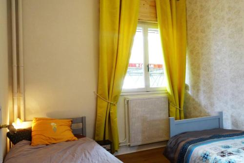 1 dormitorio con 1 cama y una ventana con cortinas amarillas en Grand appart rez de chaussée, en Moulins