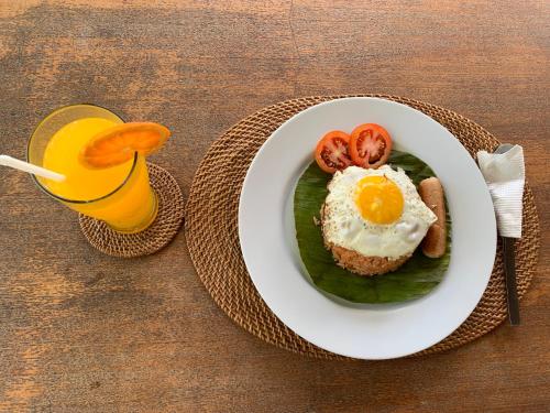 a plate of food with an egg and tomatoes on a table at Pondok Ardi Villas in Tejakula