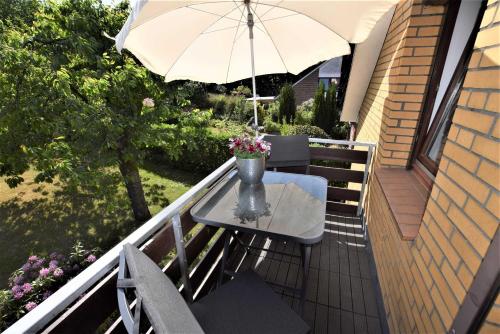 un tavolo e sedie su un balcone con ombrellone di Ferienwohnung T _ T 2 a Malente