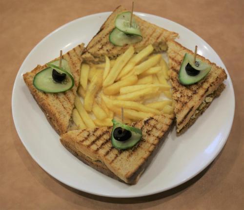a white plate with a sandwich and french fries at Hotel Buddha House Himalayan Brothers in Dharamshala