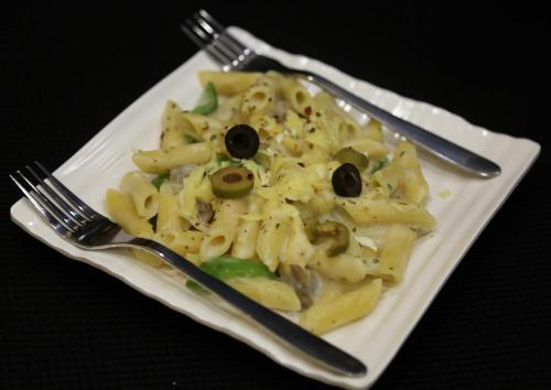a plate of pasta with black olives on it at Hotel Buddha House Himalayan Brothers in Dharamshala