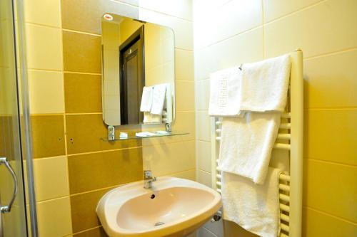 y baño con lavabo, espejo y toallas. en Pensiunea Novis, en Iaşi