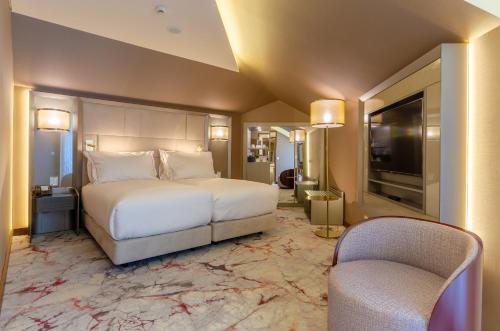 een slaapkamer met een bed en 2 stoelen en een televisie bij TURIM Boulevard Hotel in Lissabon
