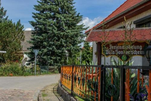 a fence in front of a building with a tree at Villa Sonnenschein in Ziethen