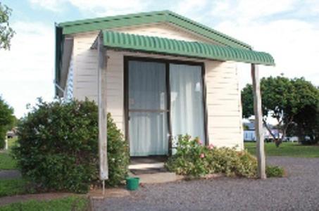 
a white house with a blue door and a blue umbrella at Abel Tasman Cabins Devonport in Devonport
