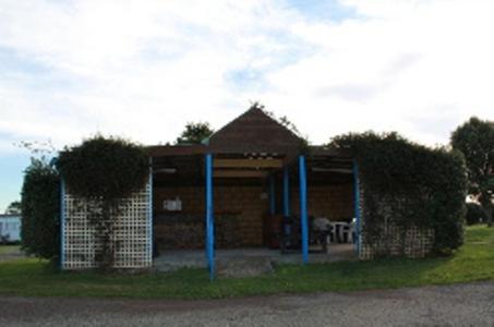 a small brick building with blue poles in the grass at Abel Tasman Cabins Devonport in Devonport