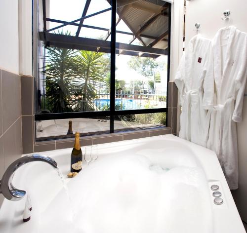 a bathroom with a white sink and a window at Majestic Oasis Apartments in Port Augusta