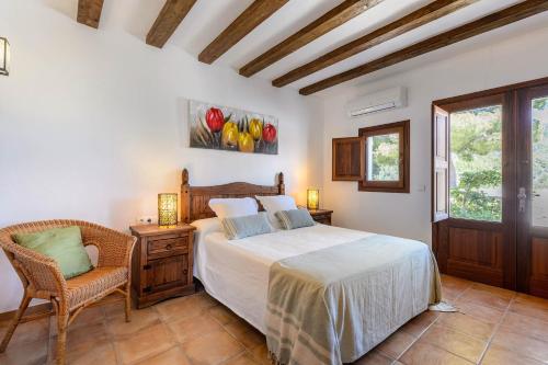 a bedroom with a bed and a chair and a window at Villa Romero I in Es Cubells