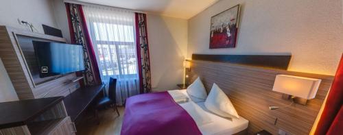 a hotel room with a bed and a television at Alpina home in Rosenheim
