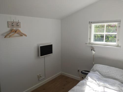 a bedroom with a bed and a tv on the wall at Cozy Guesthouse in Gilleleje