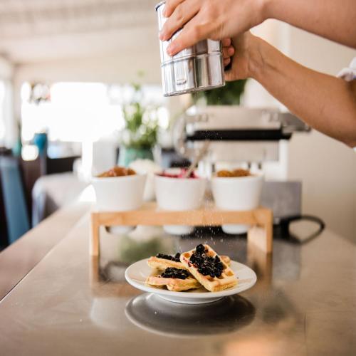 a person holding a cup and a plate of food at Hotel Giulia in Lido di Camaiore