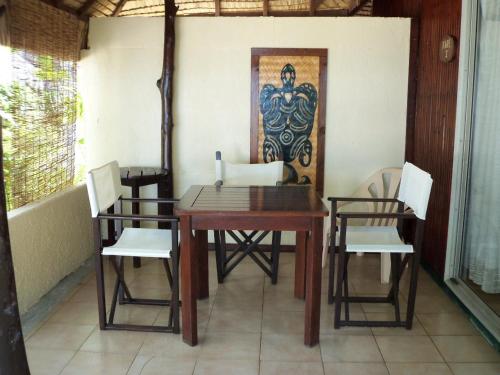 a dining room table and chairs with a painting on the wall at Village Temanuata in Bora Bora