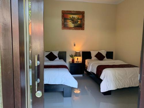 a bedroom with two beds and a picture on the wall at Pondok Ardi Villas in Tejakula