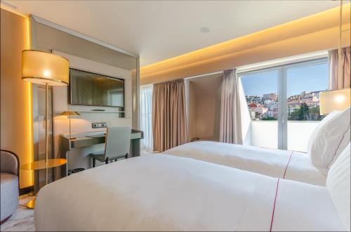 a hotel room with two beds and a window at TURIM Boulevard Hotel in Lisbon