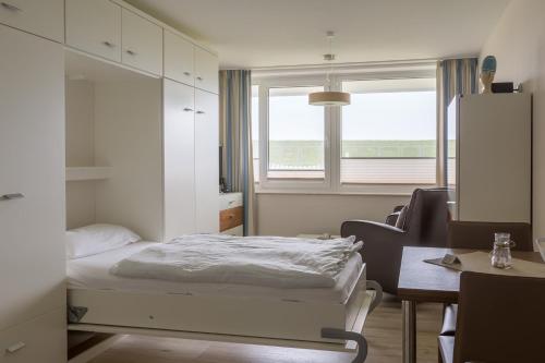 a bedroom with a bed and a desk and a window at Strandhaus Christiansen in Cuxhaven