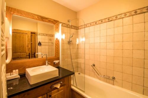 Un baño con lavabo, bañera y espejo. en Arc 1950 Chalet des lys, en Arc 1950