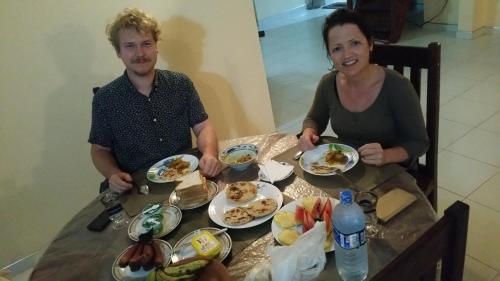 a man and a woman sitting at a table with food at Jungle Village Homestay in Pinnawala