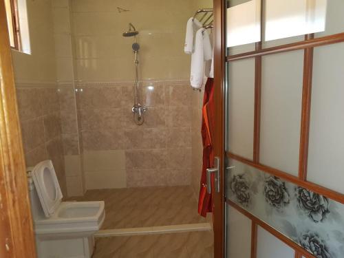 a bathroom with a shower with a toilet and a sink at Esikar Gardens Hotel in Narok