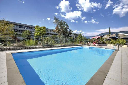 a large blue swimming pool in front of a building at Appart'City Confort Grenoble Inovallée in Montbonnot-Saint-Martin