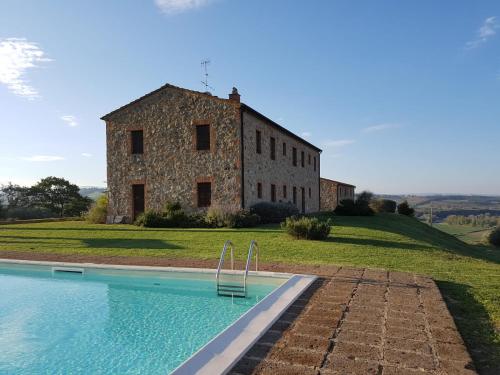 a large stone building with a pool in front of it at Podere Erba appartamento con piscina in Cinigiano