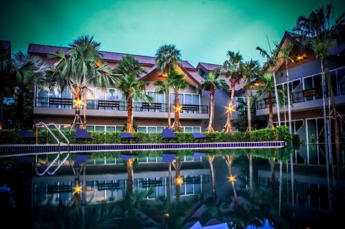 a resort with a pool and palm trees at night at Taman Resort in Phitsanulok