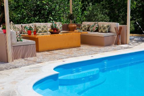 a swimming pool with couches and a table at Da Sofia in Pelekas