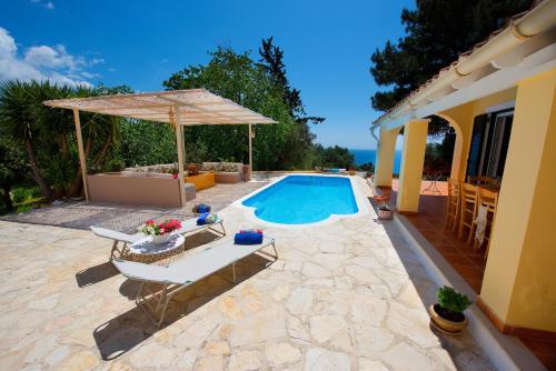 a swimming pool with a table and an umbrella at Da Sofia in Pelekas