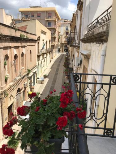 an alley with red flowers on a balcony at Cantine De Gregorio Suites in Sciacca