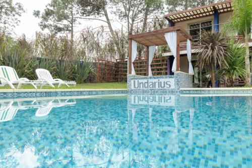 a swimming pool with chairs and a house at Undarius Hotel (exclusively gay men) in Punta del Este