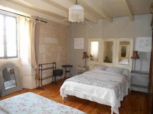 een slaapkamer met een groot bed en een spiegel bij Le vieux Prieuré in Cressé