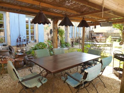 - une table et des chaises en bois sur la terrasse dans l'établissement Le vieux Prieuré, à Cressé