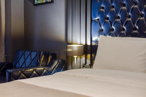 a bedroom with a bed and a leather chair at Tapis Rouge Design Boutique Hotel in Batumi