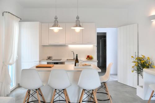 a white kitchen with white cabinets and white stools at Efi Studios in Drios