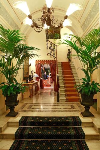 a lobby with a staircase with plants and a chandelier at Liberty Hotel in Catania