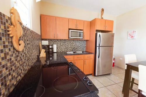 a kitchen with wooden cabinets and a stainless steel refrigerator at Island Charm Culebra - Studios & Suites - Amazing Water views in Culebra Puerto Rico! in Culebra