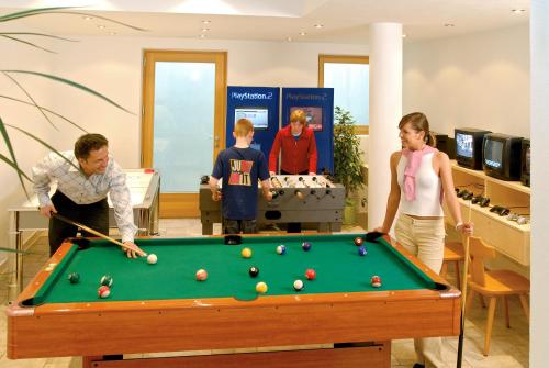 a group of people standing around a pool table at Hotel Brötz in Rasùn di Sotto