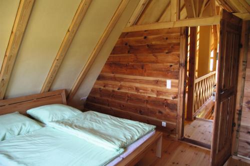 a bed in a room with a wooden wall at FH Strowota in Kolonie