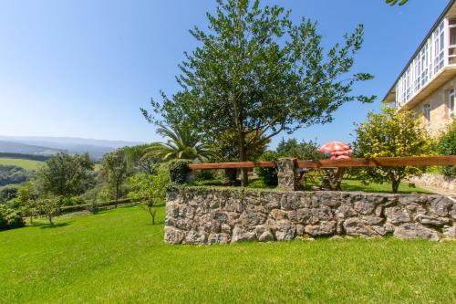 a stone wall with a bench and an umbrella at Dunas de Oyambre in Comillas
