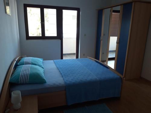 ein Schlafzimmer mit einem blauen Bett und einem Fenster in der Unterkunft Apartment Nessy (2+2) in Baška Voda