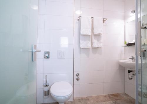a white bathroom with a toilet and a sink at Hotel Post Sindelfingen in Sindelfingen