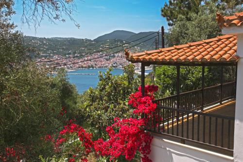 a balcony with red flowers and a view of the water at Ourania Apartment in Skopelos Town