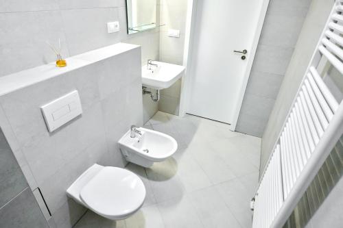 a white bathroom with a toilet and a sink at HONEST Smichov in Prague