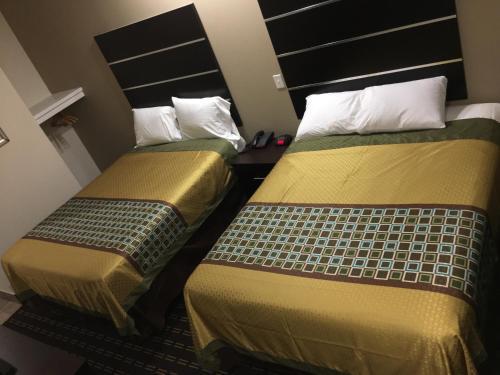 two beds sitting next to each other in a room at Americas Best Value lnn- Plaquemine in Plaquemine