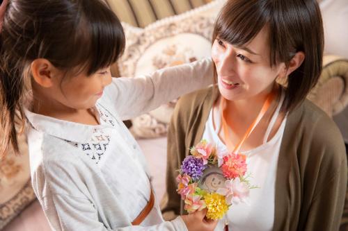 a young girl is looking at a woman holding a bouquet of flowers at Hotel Neu Schloss Otaru in Otaru