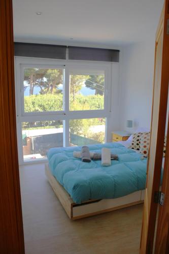 a bedroom with a large blue bed in front of a window at Aina in Cala Pi