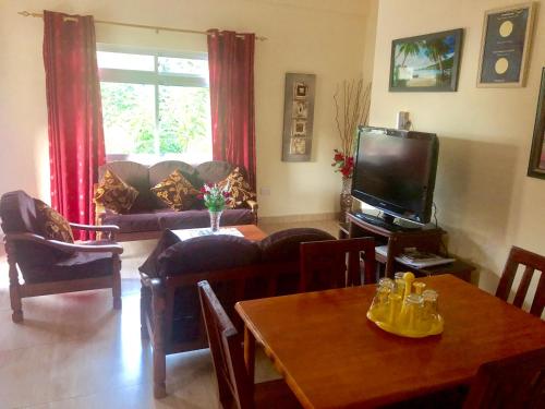 a living room with a table and a tv at Mountain Lodge in Anse Possession