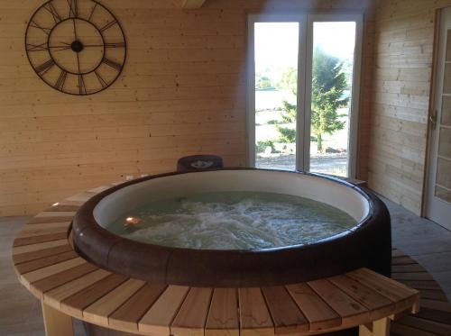 a large tub in a room with a clock on the wall at LES ROCAILLES in La Forêt-Auvray