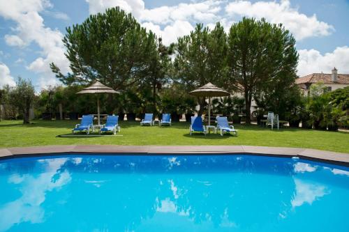 a swimming pool with chairs and umbrellas at Casas do Vale da Rainha in Portimão