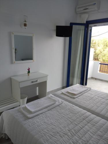 a white bedroom with a bed and a mirror at Hotel Poulakis in Skala